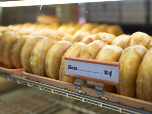 A display of glazed donuts in a bakery, with a price tag of 70 cents.