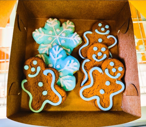 A box of decorated cookies featuring gingerbread men and a snowflake, all with colorful icing.