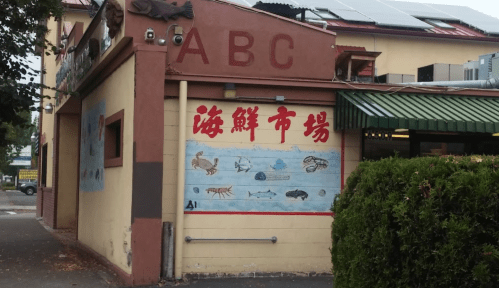 Exterior of a seafood market with colorful murals of marine life and the words "海鲜市场" (Seafood Market) prominently displayed.