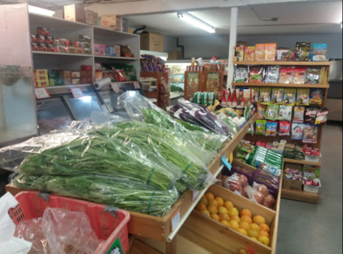 A grocery store interior featuring fresh vegetables, fruits, and various packaged goods on display.