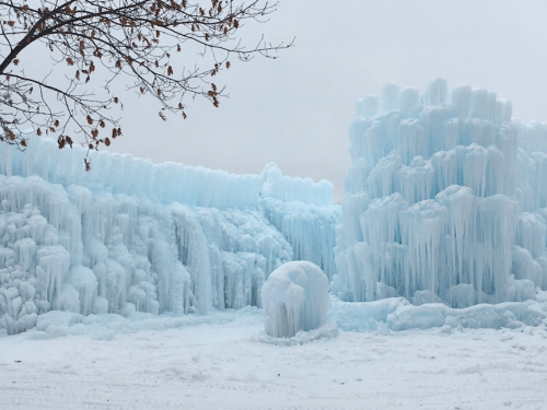 A winter scene featuring large, blue ice formations and icicles against a snowy landscape.