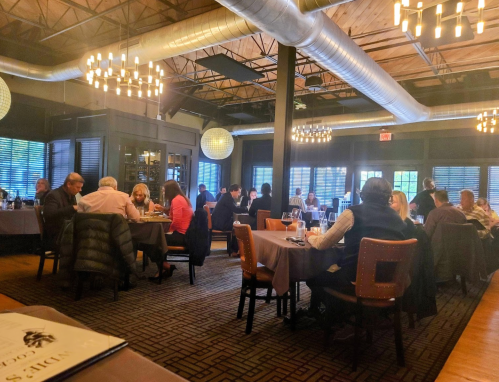 A busy restaurant interior with diners at tables, warm lighting, and modern decor.