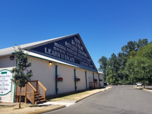 Exterior of a roller skating rink with a blue sky, trees, and a sign promoting skating lessons and healthy exercise.