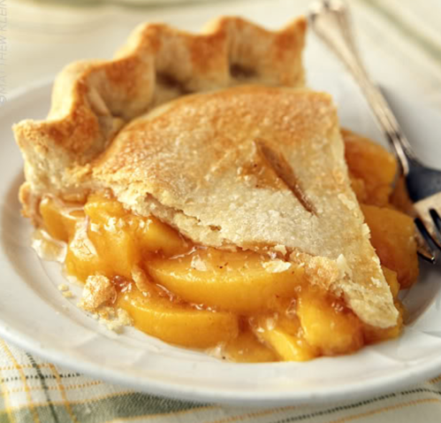 A slice of golden apple pie with a flaky crust, revealing juicy apple filling on a white plate.