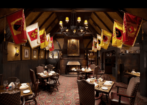 Cozy restaurant interior with wooden beams, flags hanging from the ceiling, and tables set for dining.