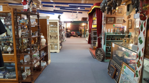 A spacious antique shop aisle lined with display cases and shelves filled with various vintage items and collectibles.