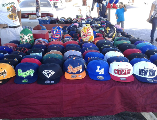 A table filled with various colorful caps and hats, featuring logos from different cities and brands.