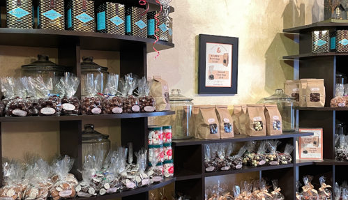 A cozy display of assorted chocolates and candies in jars and bags on wooden shelves.