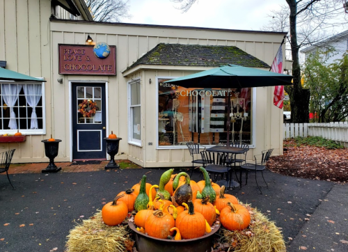 A charming chocolate shop with a pumpkin display and fall decorations outside, featuring a welcoming entrance.