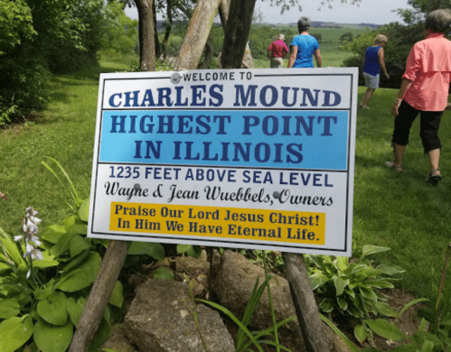 Sign welcoming visitors to Charles Mound, the highest point in Illinois, with details about elevation and ownership.