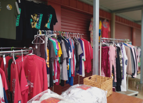 A display of various clothing items on hangers and a table, featuring colorful shirts and sweaters.