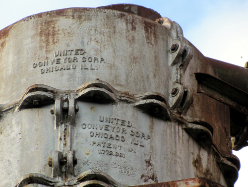 Close-up of a rusty metal conveyor component with engraved text from United Conveyor Corp, Chicago, IL.