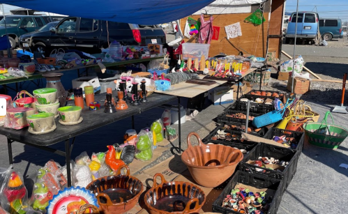 A vibrant market stall filled with colorful pottery, crafts, and various decorative items under a blue canopy.