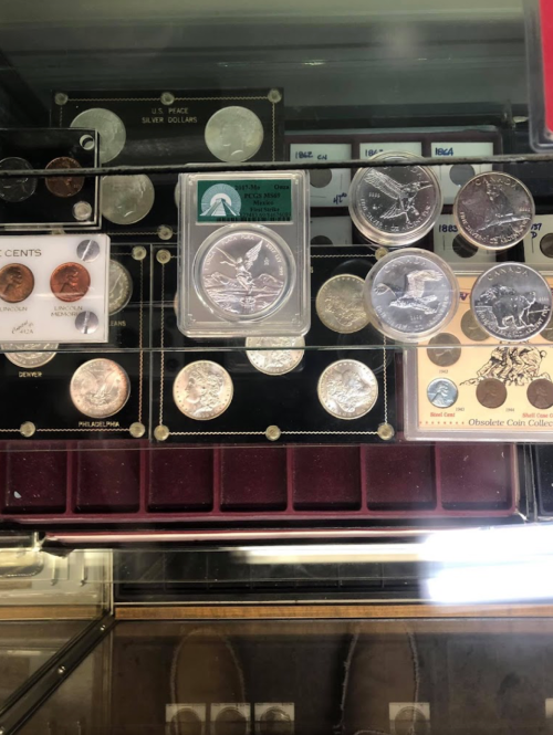 A display case featuring various coins, including silver dollars and collectible pieces, arranged neatly.