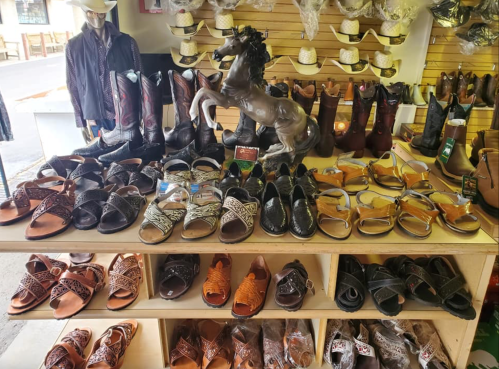 A display of various shoes, including sandals and boots, with a horse statue in the center.
