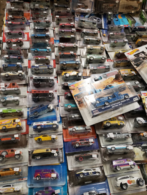 A collection of various toy cars displayed in packaging, arranged closely together on a table.