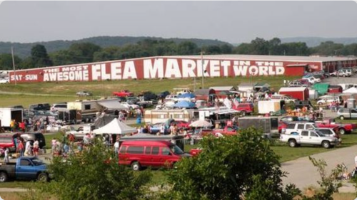 A bustling flea market scene with numerous vendors, cars, and shoppers, set against a large sign reading "Awesome Flea Market."