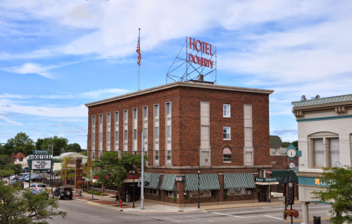 Historic brick building with a "Hotel Dobby" sign, featuring a flag and awnings, set against a cloudy sky.