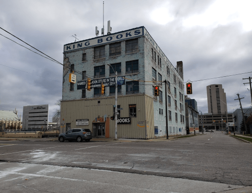 A large, weathered building with "King Books" signage, located at an intersection under a cloudy sky.