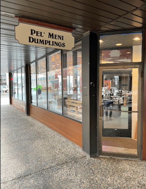 Exterior view of Pel' Meni Dumplings restaurant, featuring a sign and glass entrance under a covered walkway.