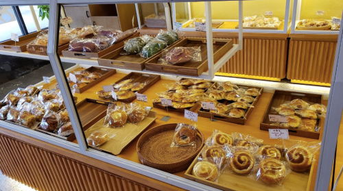 A display of assorted baked goods in a bakery, neatly arranged in trays and wrapped in plastic.