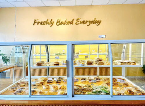 Display case filled with various baked goods, with a sign above reading "Freshly Baked Everyday."