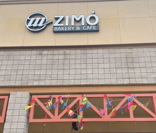 Sign for Zimó Bakery & Cafe with colorful bunting decorations below it.