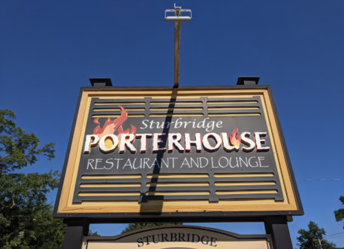 Sign for Porterhouse Restaurant and Lounge in Sturbridge, featuring bold lettering and a clear blue sky background.