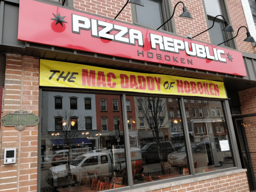 A storefront with a red sign reading "Pizza Republic" and a banner that says "The Mac Daddy of Hoboken."