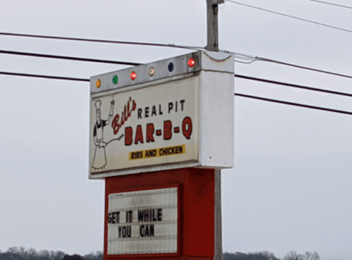 Sign for Bill's Real Pit Bar-B-Q featuring ribs and chicken, with a message: "Get it while you can."