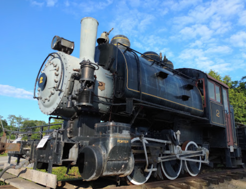 A vintage steam locomotive with a black and silver exterior, numbered "2," against a blue sky.