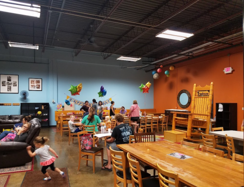A lively community space with tables, chairs, and colorful decorations, where people gather and socialize.