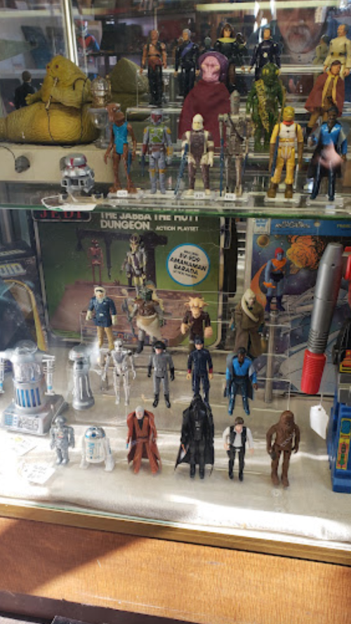 Display case filled with various Star Wars action figures and collectibles, including droids and characters from the series.