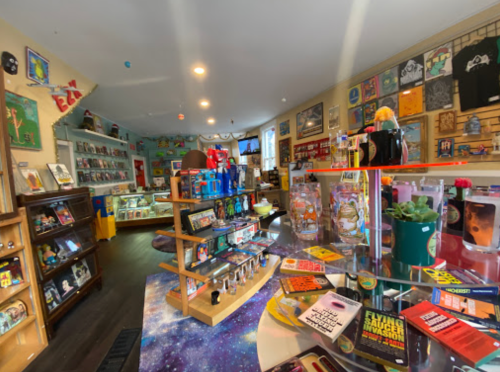 A colorful vintage shop filled with collectibles, books, and quirky decor, featuring shelves and display cases.