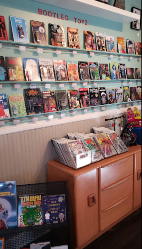 A colorful display of comic books and toys on shelves, with a vintage cabinet in the foreground.