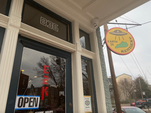 A storefront with "Earth to Kentucky" sign and "Open" in the window, featuring a UFO graphic.