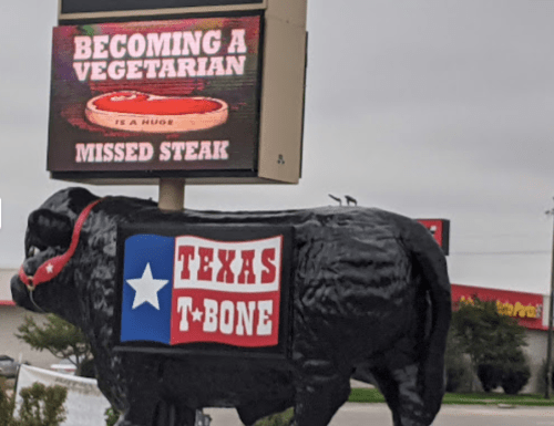 A large cow statue in front of a sign that reads "Becoming a Vegetarian is a Huge Missed Steak" at Texas T-Bone.