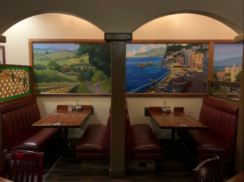 Cozy restaurant interior with red booths and a mural of a coastal landscape on the wall.
