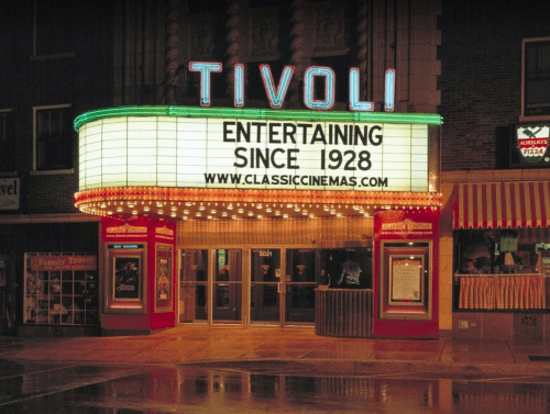 Tivoli Theater marquee at night, featuring "Entertaining Since 1928" and a website link, with a rainy street view.