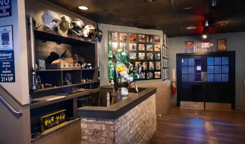 A themed bar interior featuring memorabilia, a Boba Fett figure, and a display of framed photos on the wall.