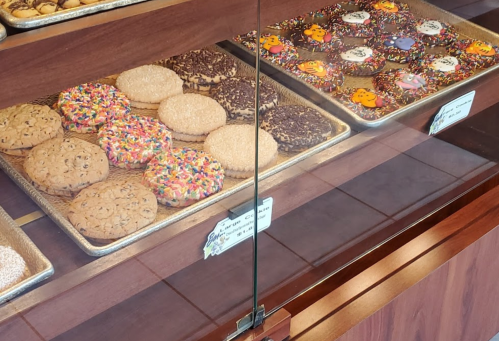 A display case filled with various cookies, including chocolate chip, sprinkle-covered, and decorated cookies.