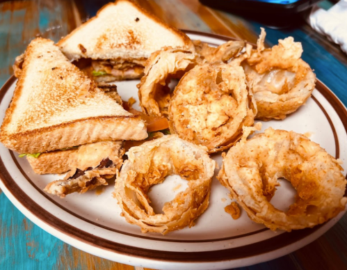 A plate with a toasted sandwich and several crispy, round fried snacks.