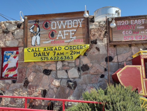 Sign for Cowboy Cafe featuring a cowboy graphic, with details for call-ahead orders and operating hours.
