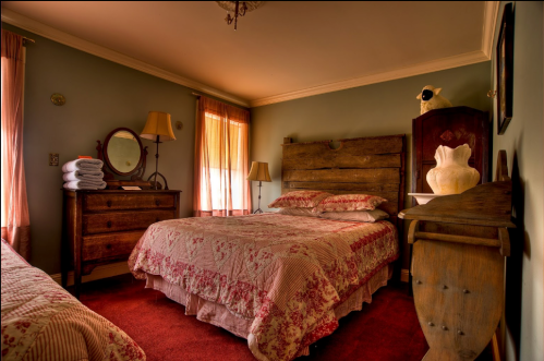 Cozy bedroom with a wooden bed, dresser, and warm lighting, featuring floral bedding and vintage decor.