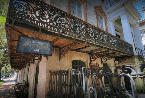 A vintage building with a decorative balcony and a sign reading "Alex Rasin Antiques 441."