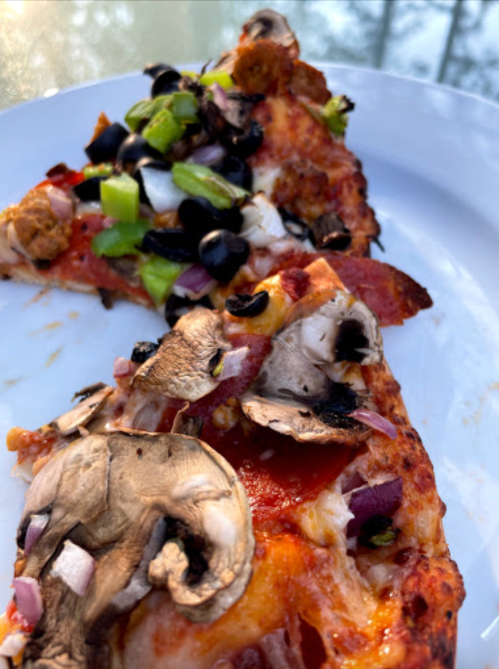 Two slices of pizza on a plate, topped with pepperoni, mushrooms, black olives, green peppers, and onions.
