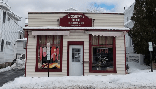 A small Polish restaurant and deli with a red sign, snow in front, and an "Open" sign in the window.