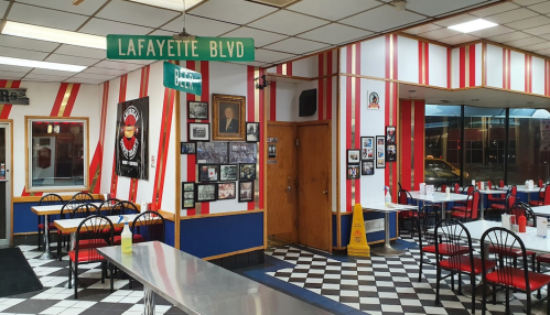 Interior of a diner with red and white striped walls, checkered floor, and a Lafayette Blvd street sign.