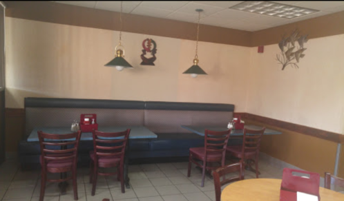A cozy restaurant interior featuring a booth, tables, and simple decor with pendant lights and wall art.