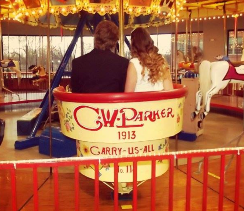 A couple sits together on a vintage carousel ride, enjoying the view and each other's company.